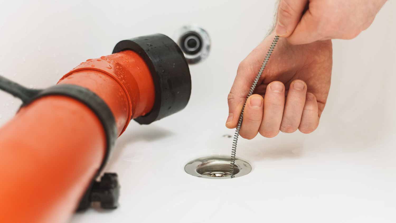 A plumber skillfully using a drain snake to resolve common drain clogs in sinks, toilets, and showers.